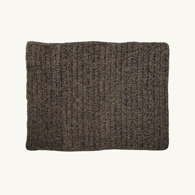 The Natural Black Seagrass Carpet featuring a rectangular shape with a striking natural and black color combination. Crafted from raffia, sisal, and palm, this rug offers both elegance and durability for any room.