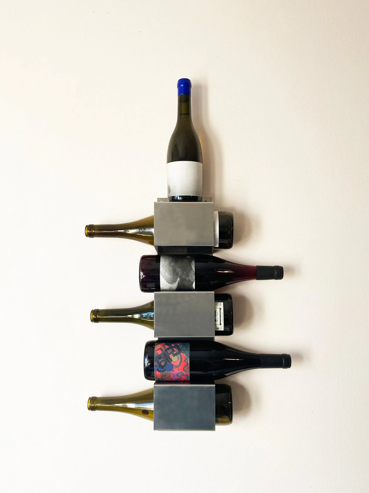 Wall-mounted wine shelf "100.80.1" by OK.VMH, modern aluminum design, slightly tilted for secure bottle storage