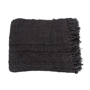 Black cotton throw with a waffle texture and tassels, styled on a rustic wooden chair for a chic and inviting look
