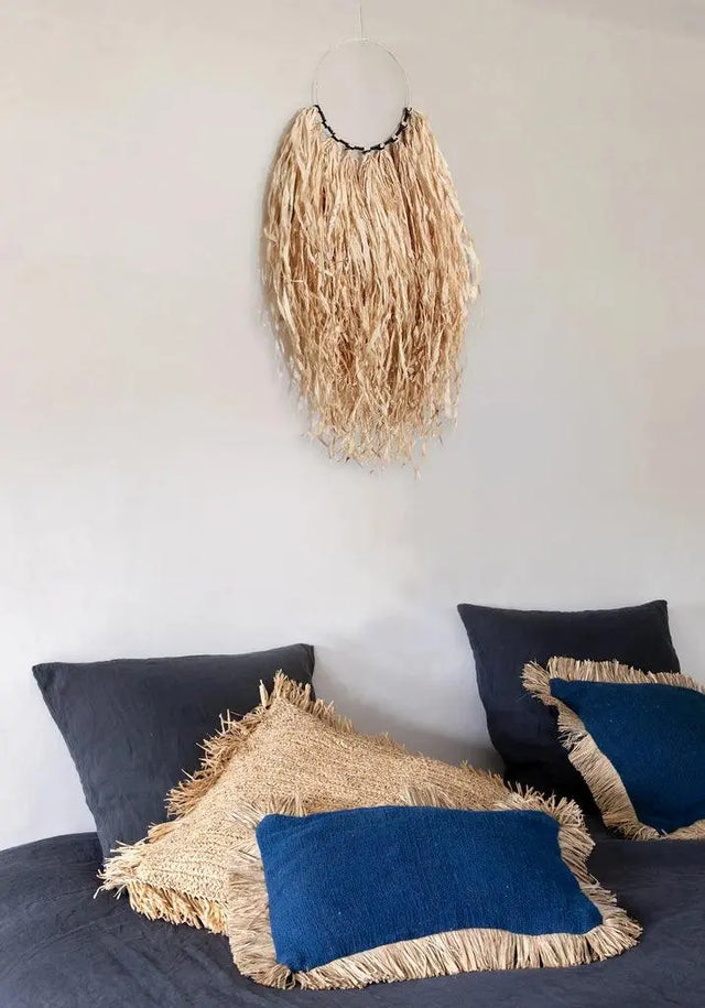 Rectangular blue cushion cover with raffia fringes, a charming addition to any indoor or outdoor boho-inspired space