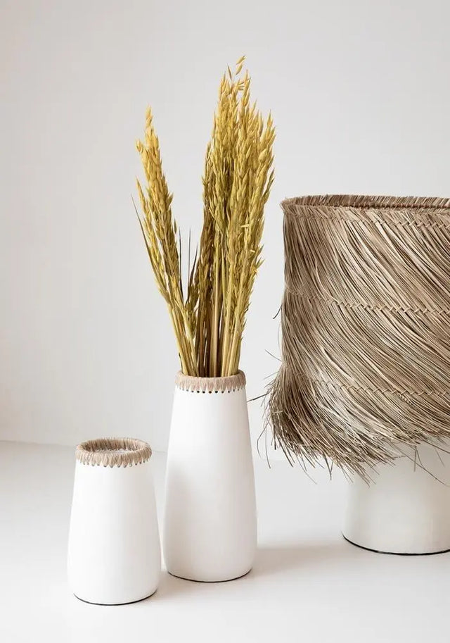 The Large Sneaky Vase, crafted from natural white terracotta with a raffia accent, is perfect for showcasing dried flowers in small spaces