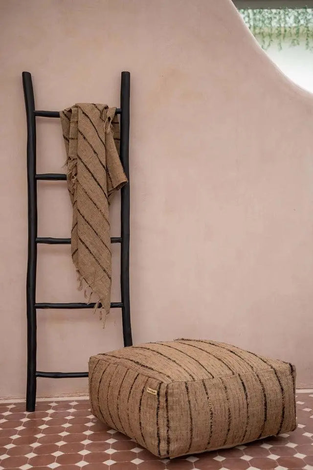 'The Oh My Gee' Pouffe in beige and black styled in a cozy living room, adding a bohemian accent to the space.