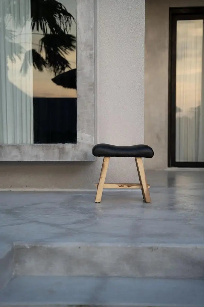 Versatile suar wood stool with a modern matte black leather seat, perfect for dining, side, or accent use