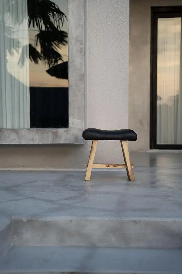 Versatile suar wood stool with a modern matte black leather seat, perfect for dining, side, or accent use