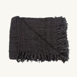 Luxurious black cotton throw with a modern waffle texture and decorative tassels, ideal for living room decor