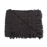 Close-up view of the modern waffle texture and decorative tassels on the black cotton throw