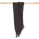 Black cotton throw with decorative tassels, perfect for cozying up indoors or adding charm to outdoor settings